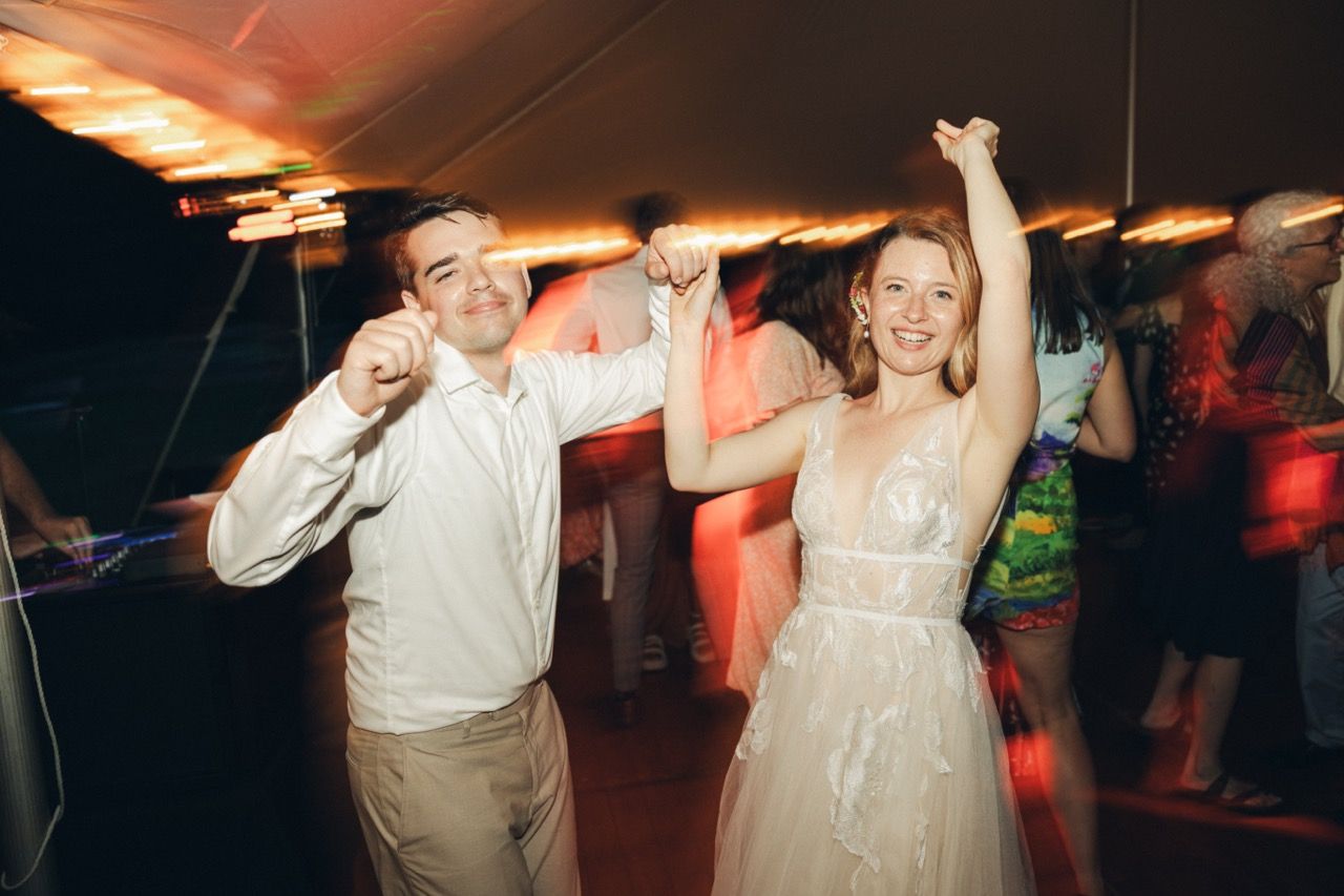 Joyful bride and groom dancing together at lively wedding reception under warm lights. Westport Ma Miranda Photo & Co