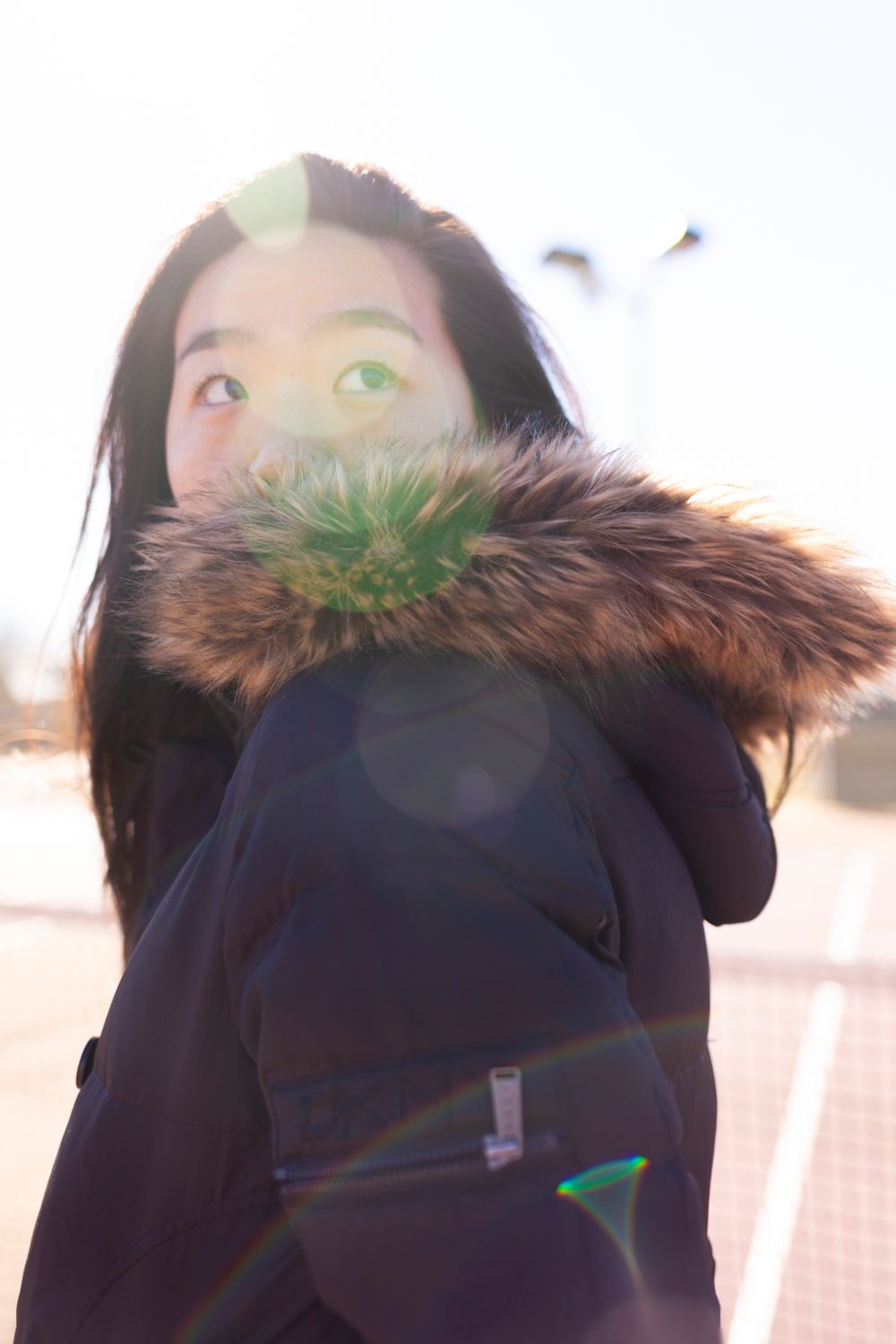 A person wearing a coat looking up towards the sky.