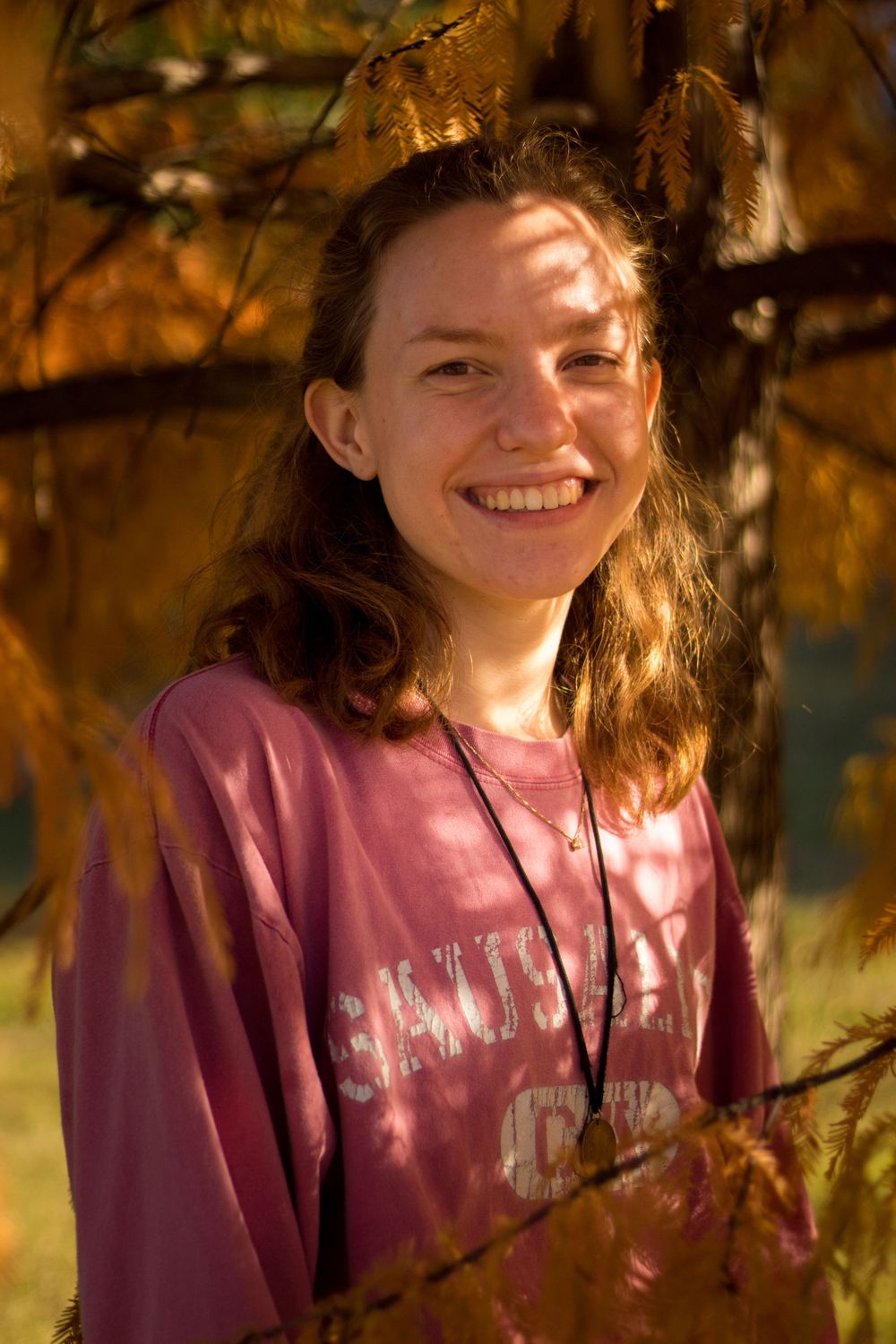 A person under a tree smiling at the camera.