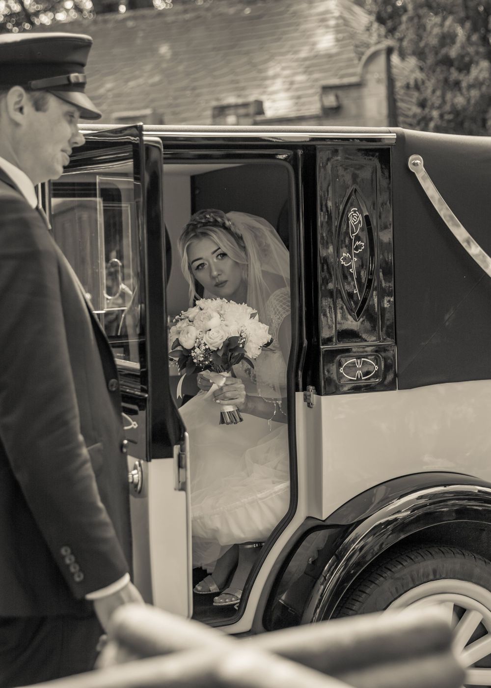 bride peeking through the open wedding car door outside west tower aughton