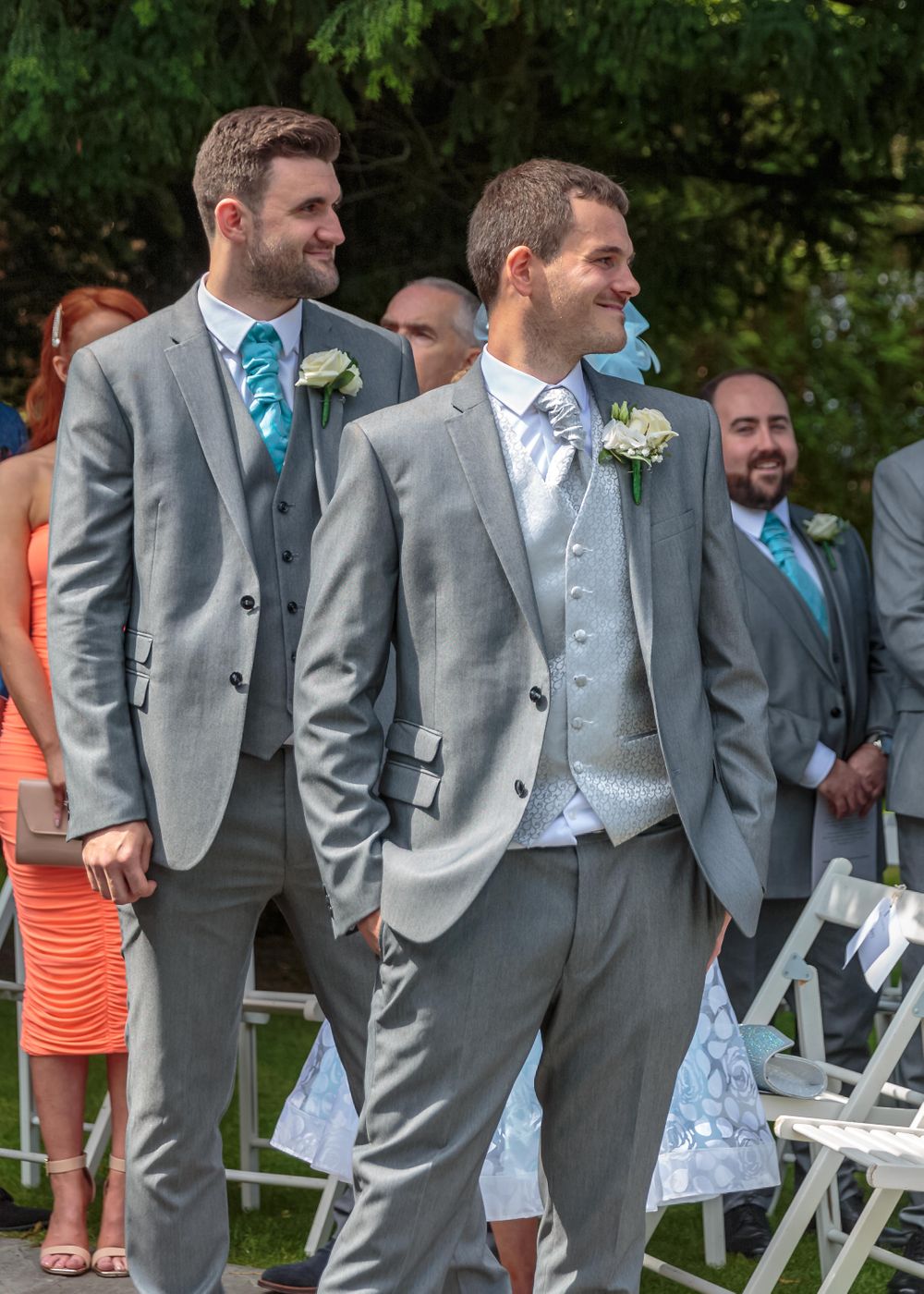 groom stood with his best man smiling as he looks back up the aisle at his bride