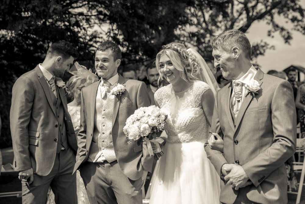 bride smiling as she arrives at the top of the aisle arm in with her father in the garden at west tower aughton