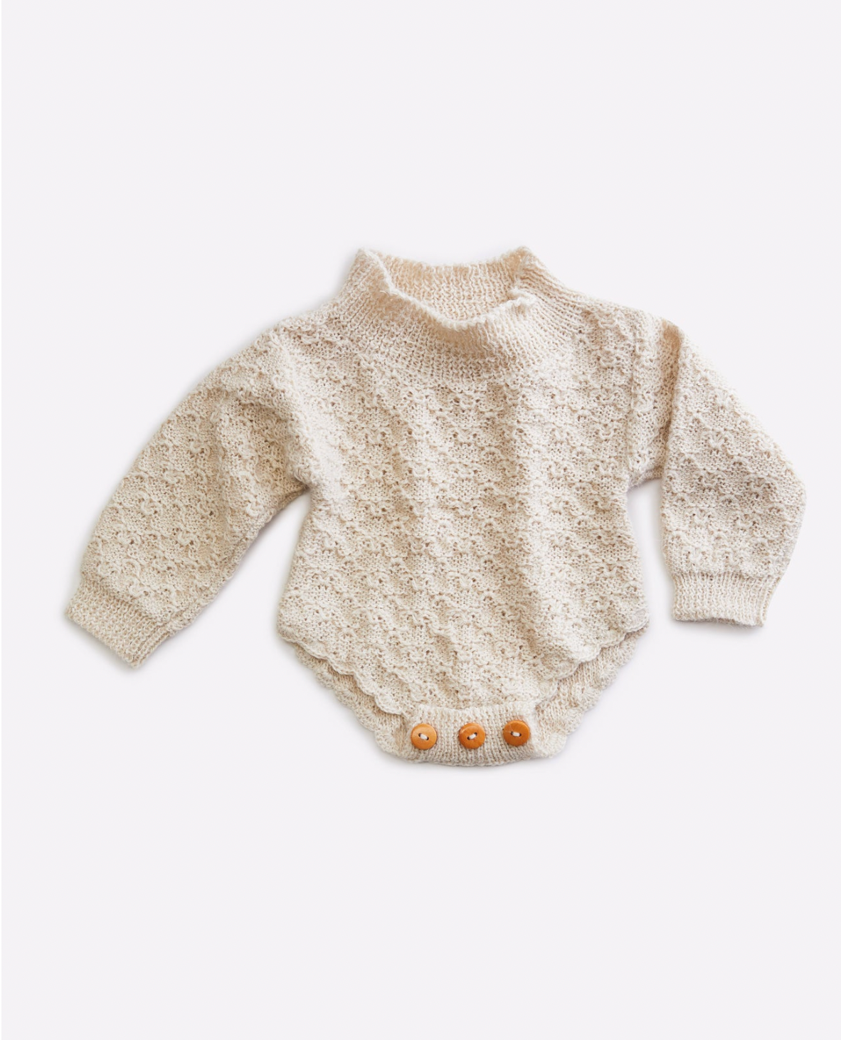 Cream colored knit baby bodysuit with decorative pattern and wooden buttons.