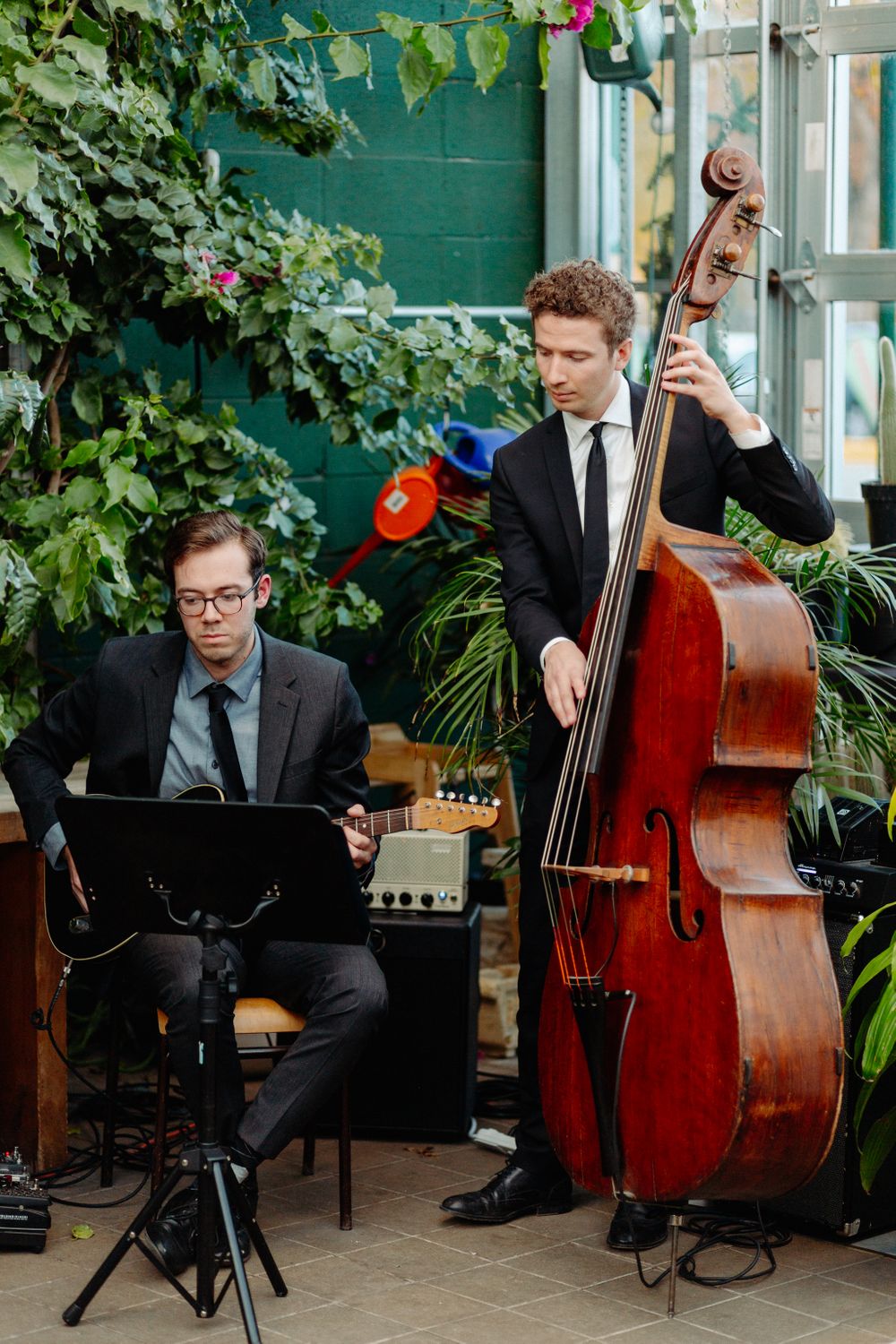 Musicians performing with upright bass and music stand in a lush garden setting.
