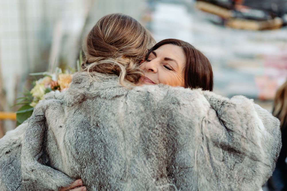Two people sharing a close embrace while wearing a soft grey fur coat.
