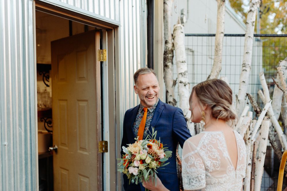 A couple in wedding attire standing in a doorway during an intimate moment.