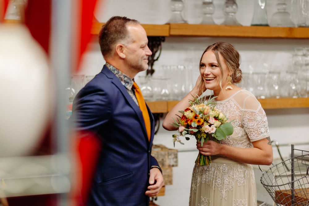 A couple sharing a moment at an indoor venue with glass decor and floral arrangements.