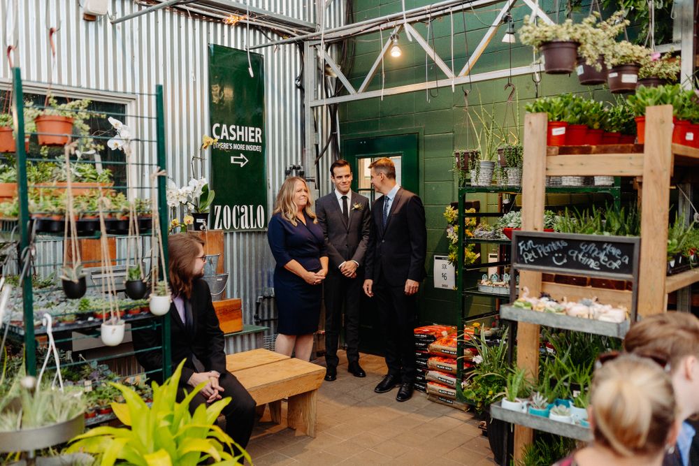 Group gathering in a garden center with shelves of plants and industrial decor.