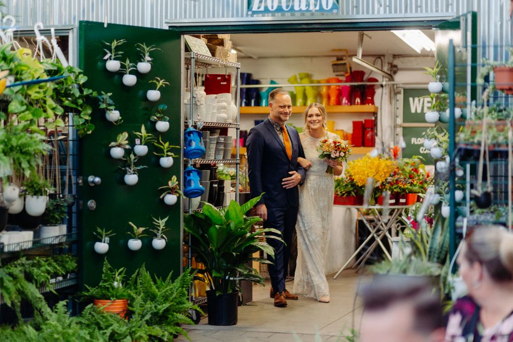 View of a flower shop entrance with greenery and colorful floral displays.