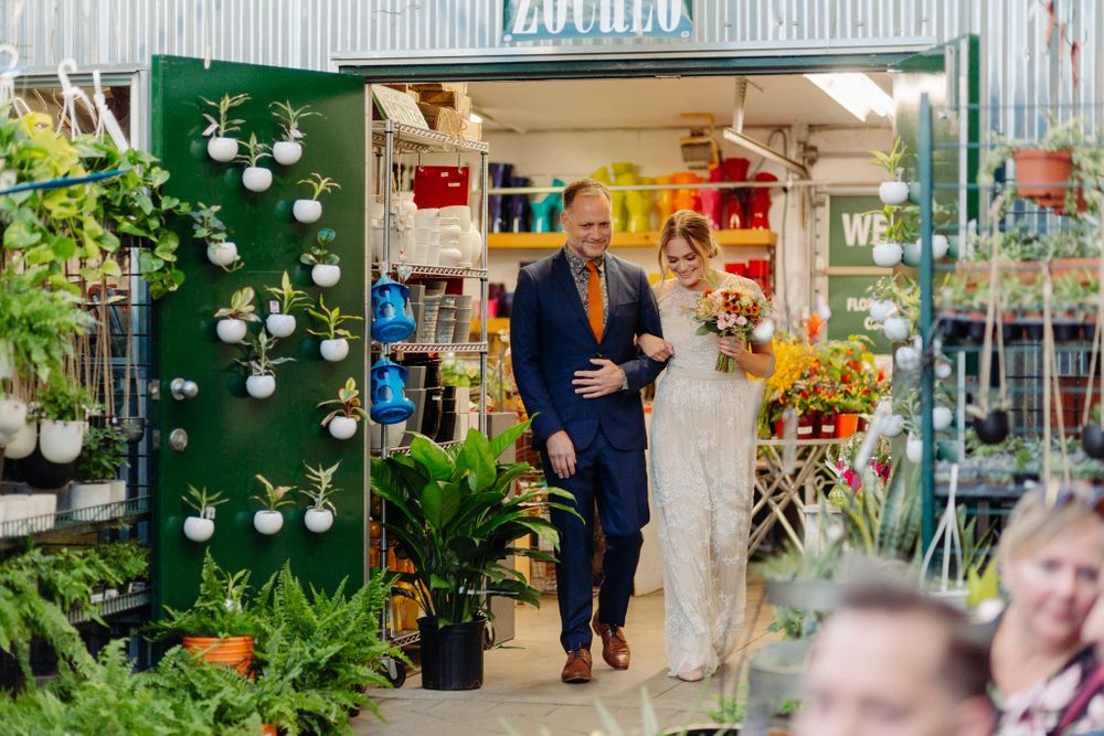 Wedding ceremony entrance through a flower shop with white floral wall decorations.