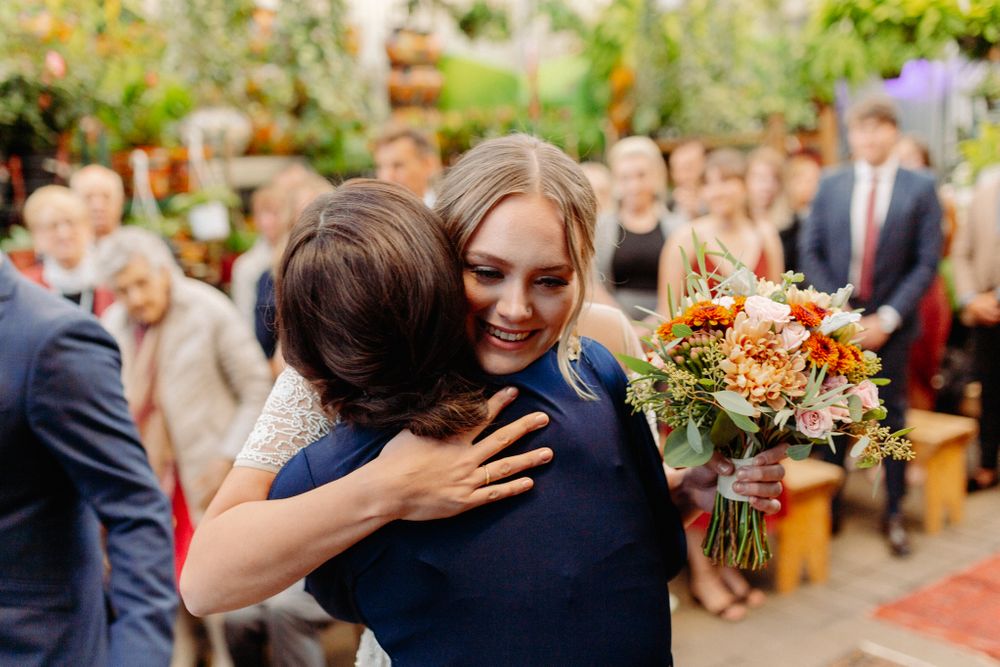 Wedding gathering in greenhouse with autumn florals and decorative red carpet.