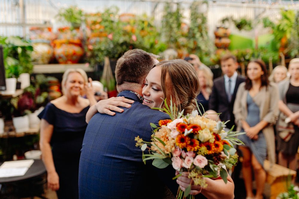 Intimate greenhouse wedding ceremony with white lace dress and floral decorations.