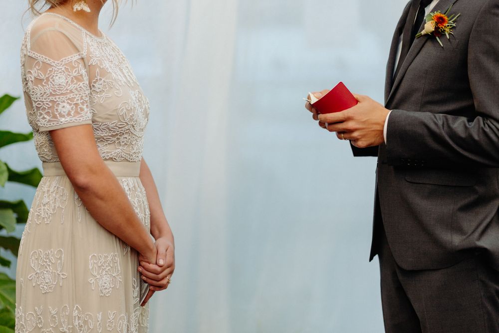 Close-up of couple during wedding ceremony with groom holding red book.