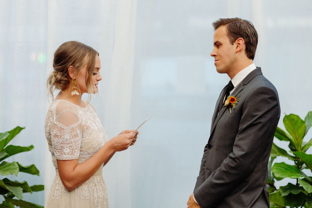 Couple exchanging vows while reading from papers during wedding ceremony.