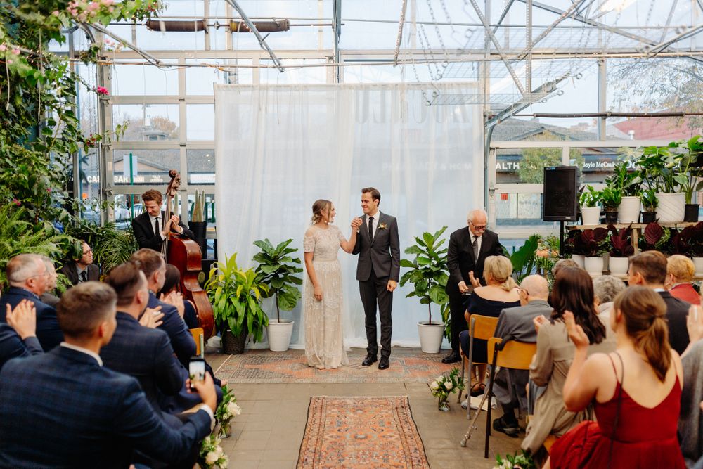 Wedding celebration in greenhouse venue with white draping and vintage decor.