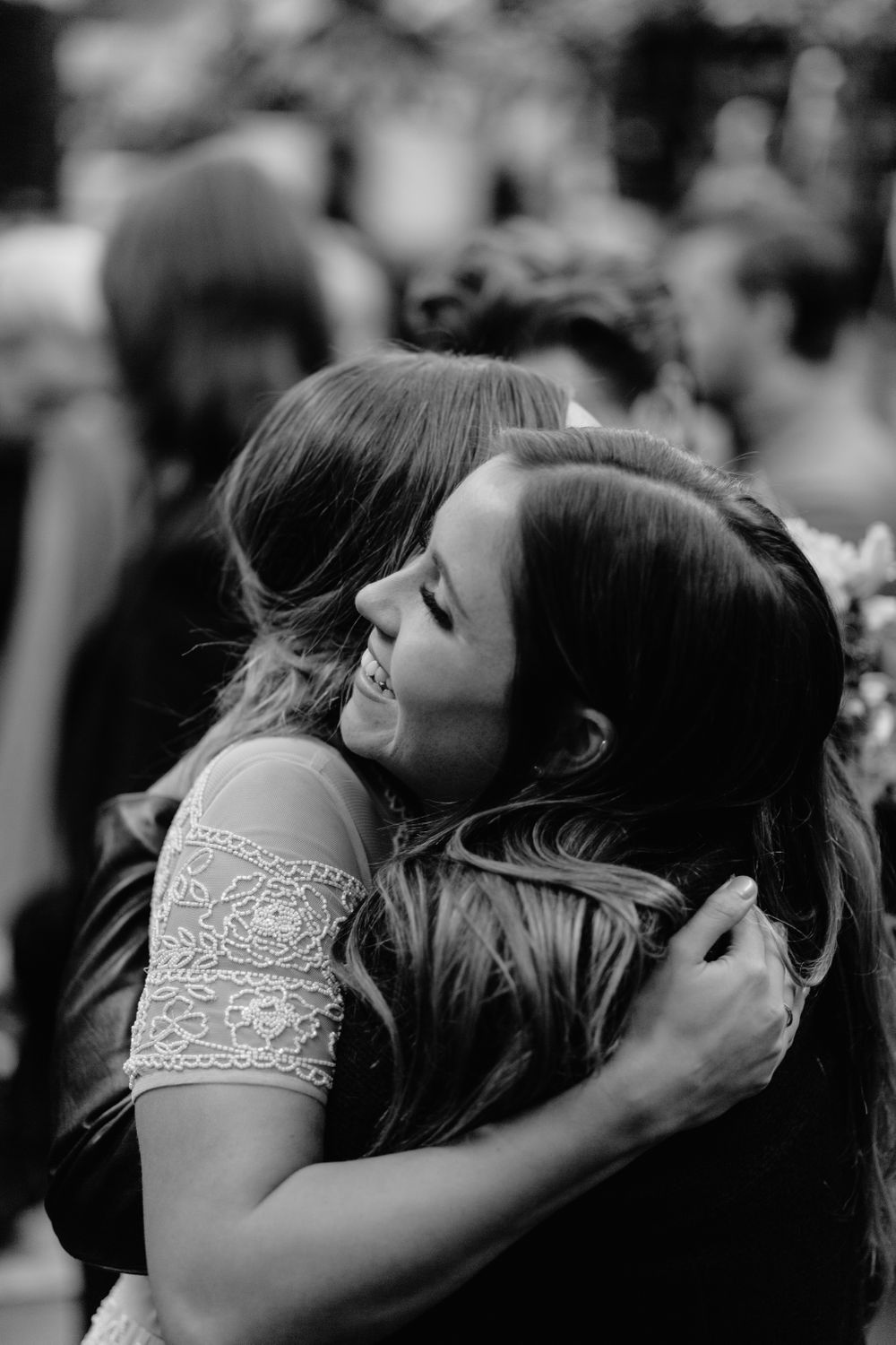 Black and white photo capturing emotional embrace during wedding reception celebrations.