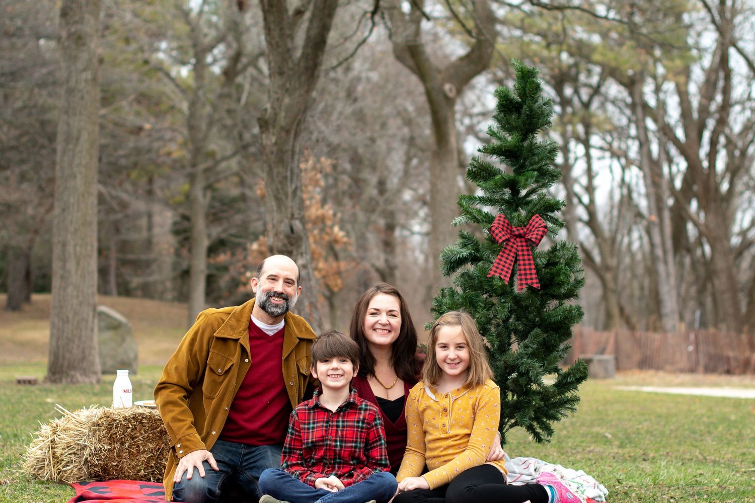 Series of playful photos showing a family lounging on a blanket with a decorated Christmas tree outdoors.
