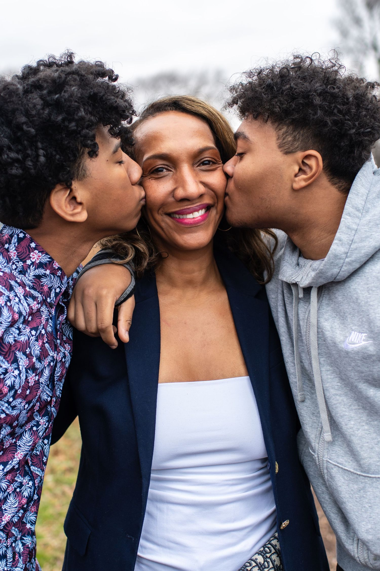 Family moment captured with sweet kisses and smiles against neutral background.