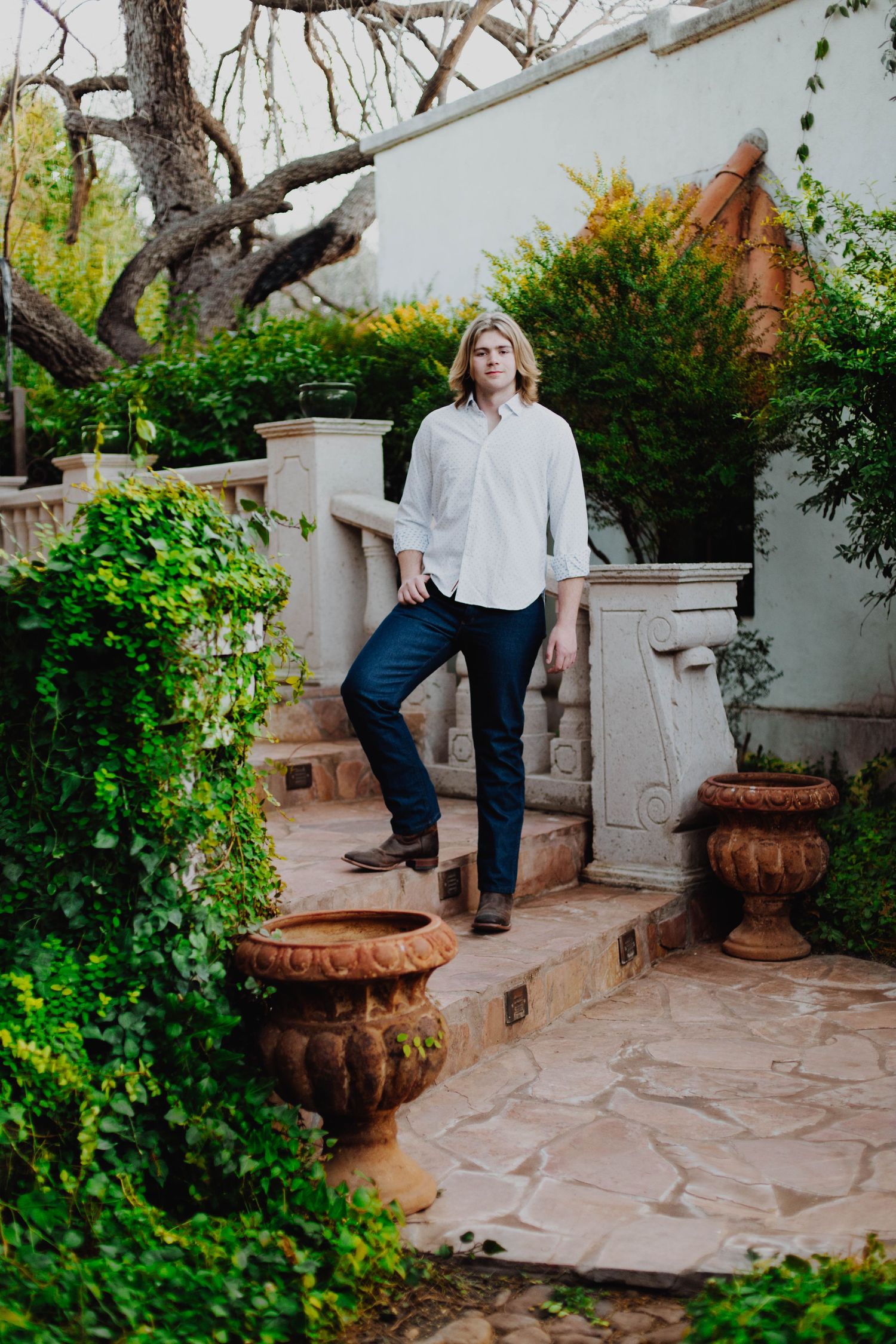 Fashion portrait on stone steps with lush garden landscaping.