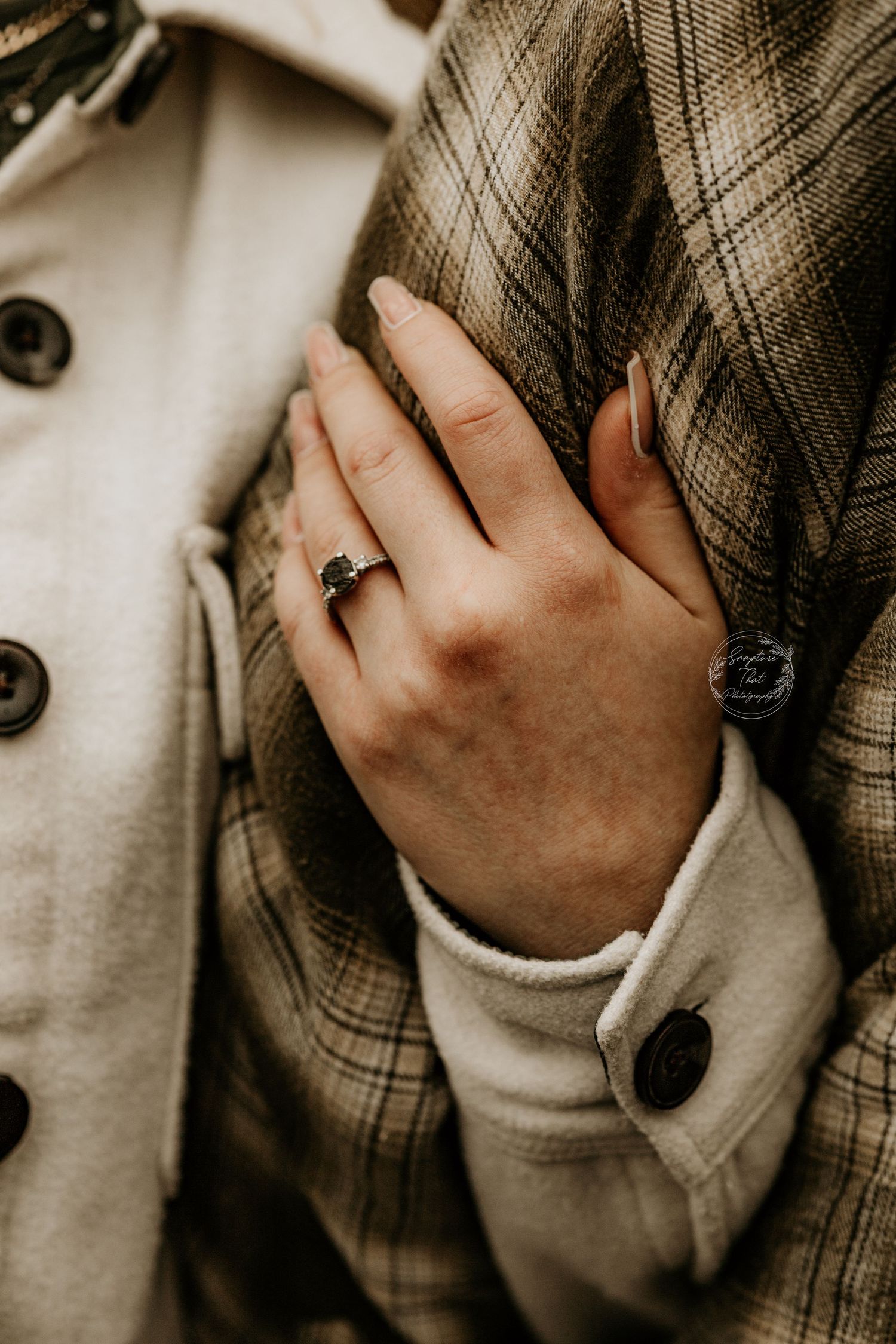 Close-up of hands gently touching plaid fabric in muted tones.