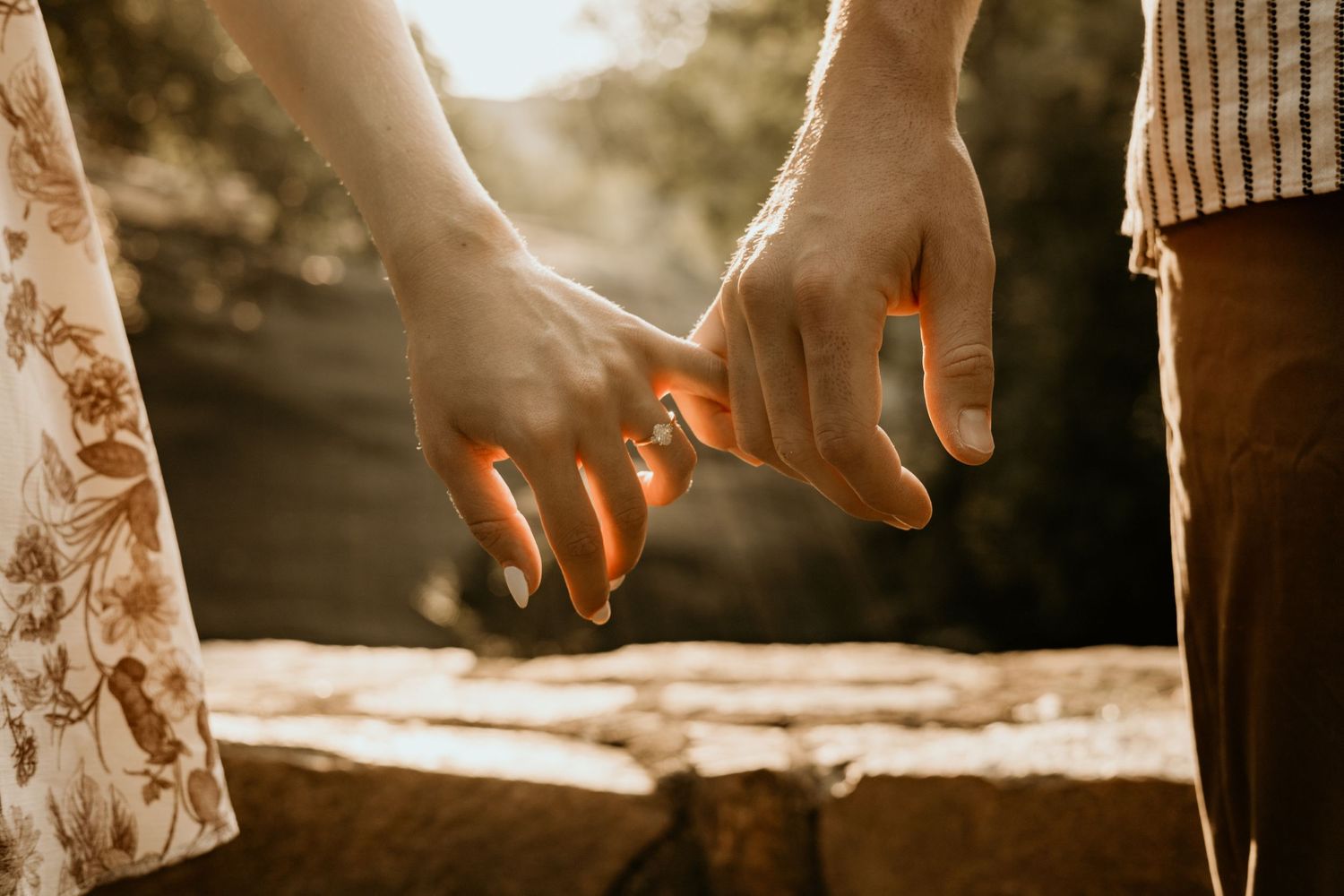 Silhouetted hands reaching towards each other in warm backlit setting.