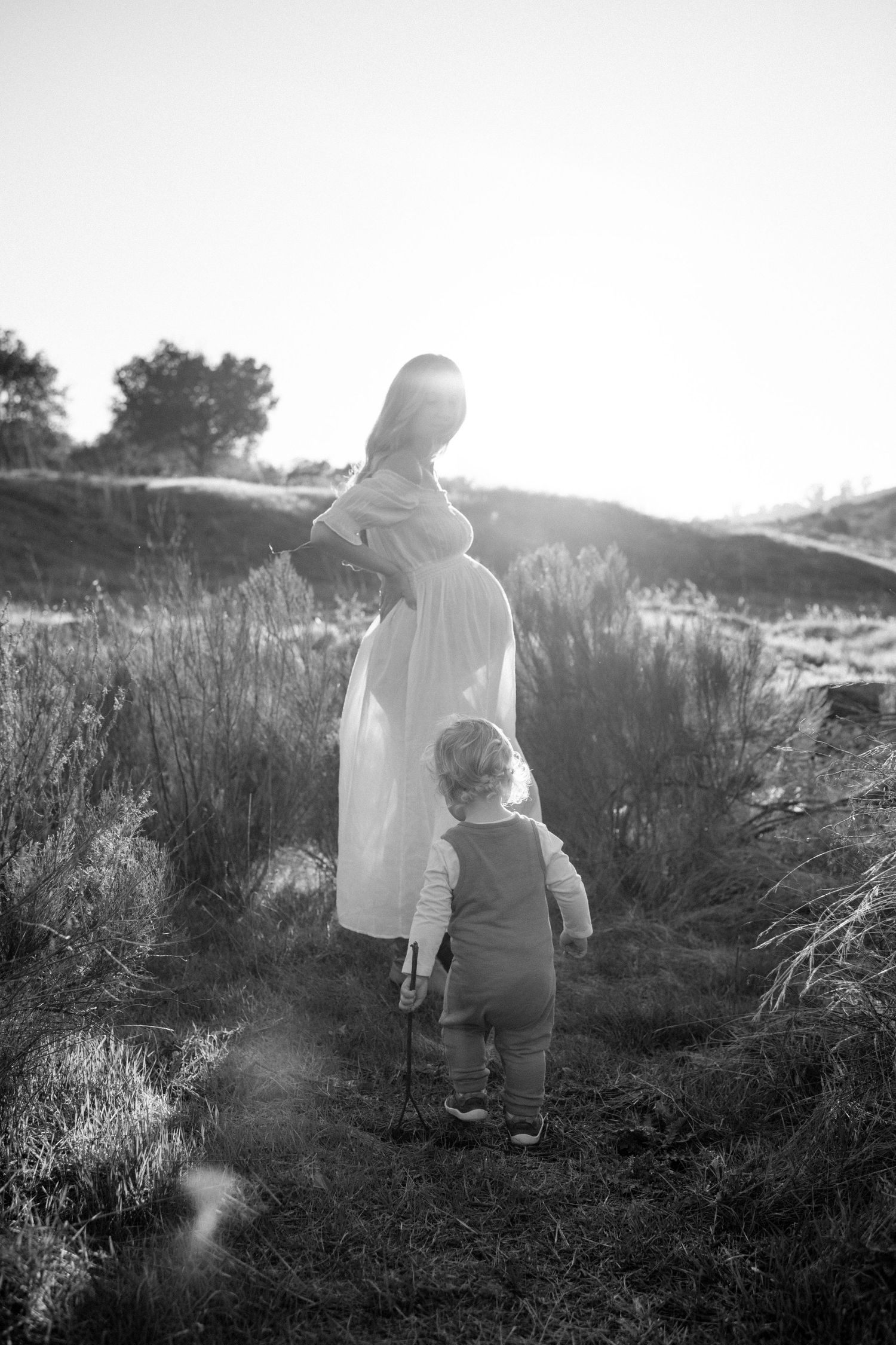 Pregnant mama in field with toddler son during maternity photoshoot in San Diego.