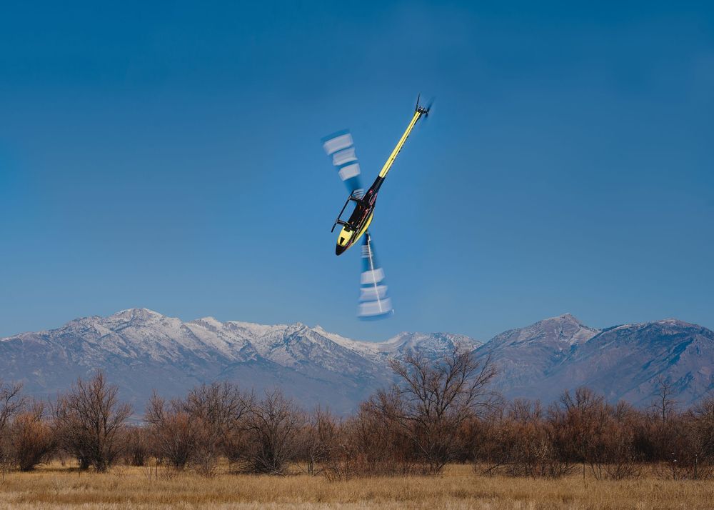Freestyle skier performs dramatic backflip against snow-capped mountain backdrop.