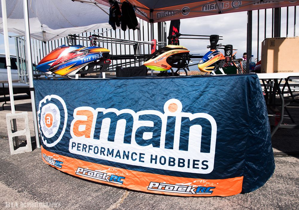 RC helicopters displayed on Domain Performance Hobbies branded table at event.