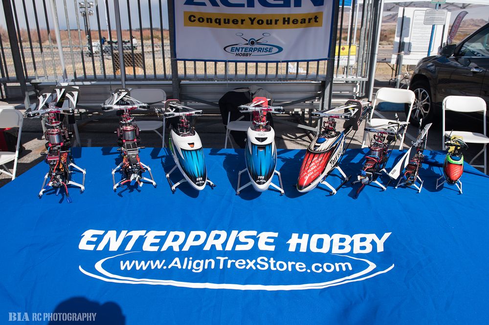 Display of RC helicopters on blue Enterprise Hobby branded mat at trade show.