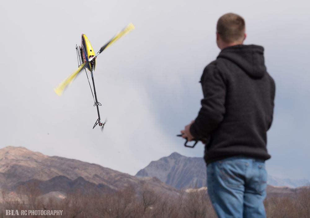 RC helicopter pilot flying aircraft against mountainous backdrop during sunset.