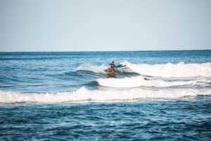 Person riding jet ski creates wake across blue ocean waters.