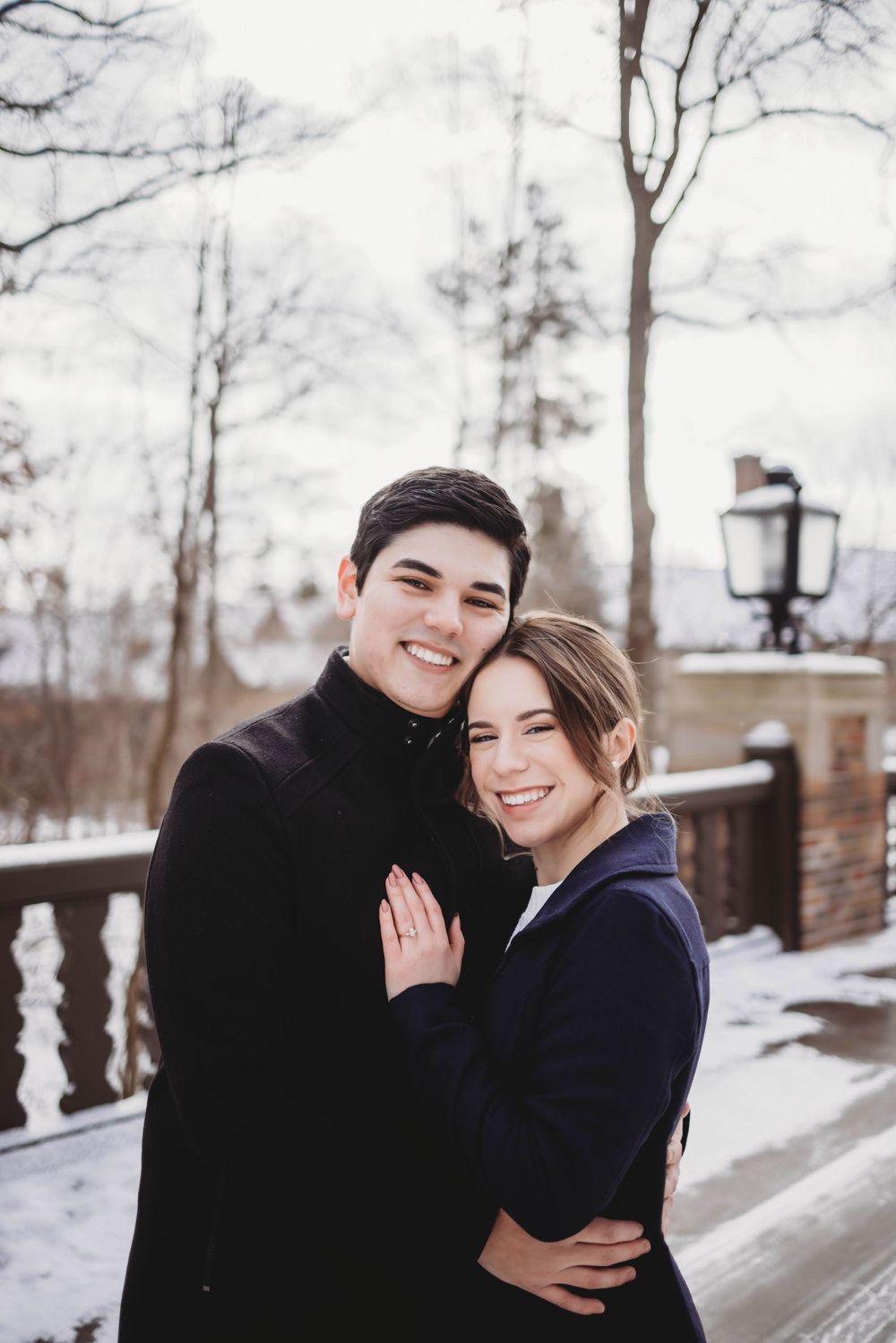 A winter engagement photo session with a couple in cozy coats against a snowy backdrop.