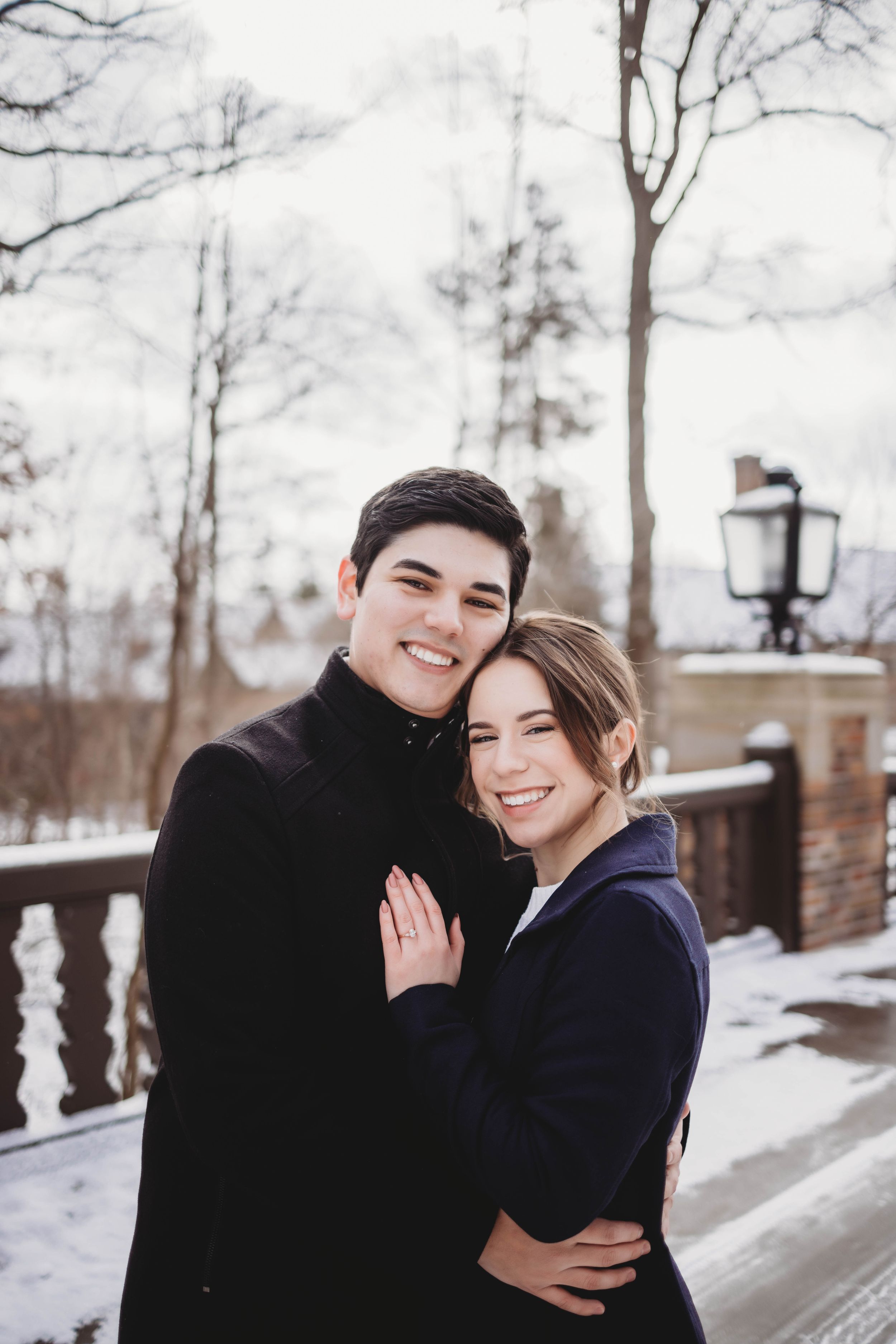 A winter engagement photo session with a couple in cozy coats against a snowy backdrop.