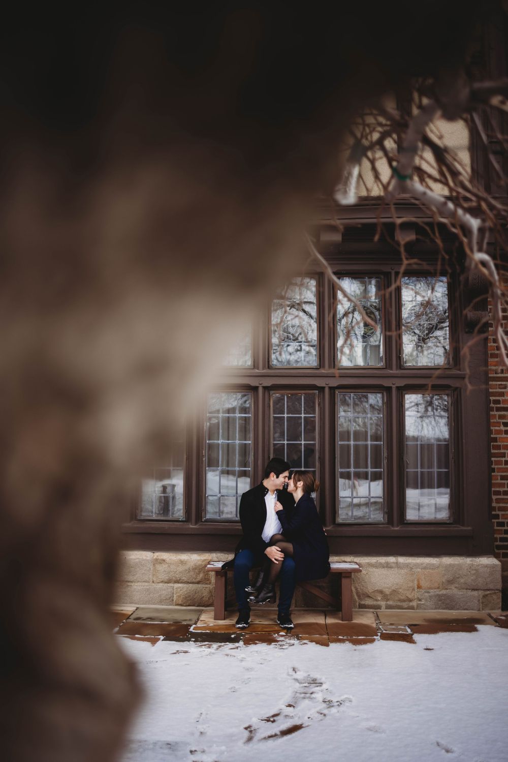 A cozy winter scene through a window frame with snow on the ground.