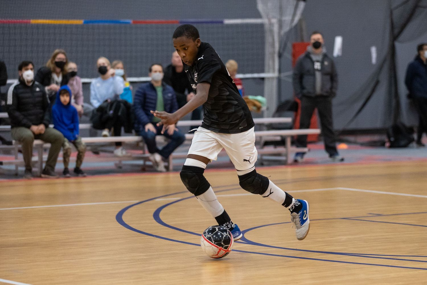 Athletes compete in indoor wheelchair basketball game on gymnasium court.