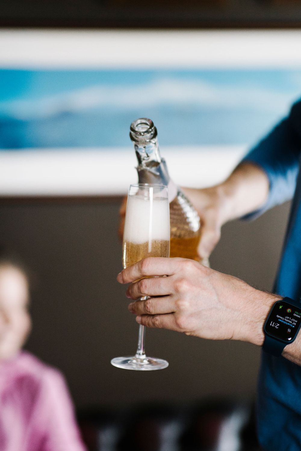 Hand holding a champagne glass being filled with bubbling wine.