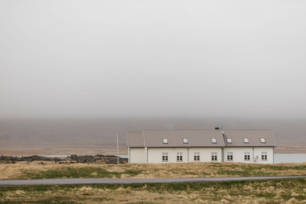 A white building sits alone on the misty Icelandic coastline.