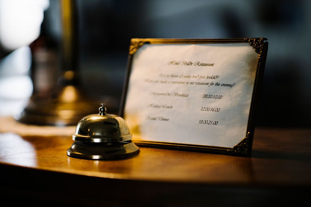 A service bell sits next to a document on a wooden desk surface.