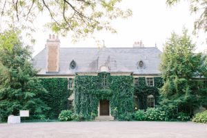 Historic stone mansion covered in lush green ivy with traditional architecture.