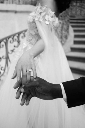 Black and white photo showing hands with wedding rings in an intimate moment.