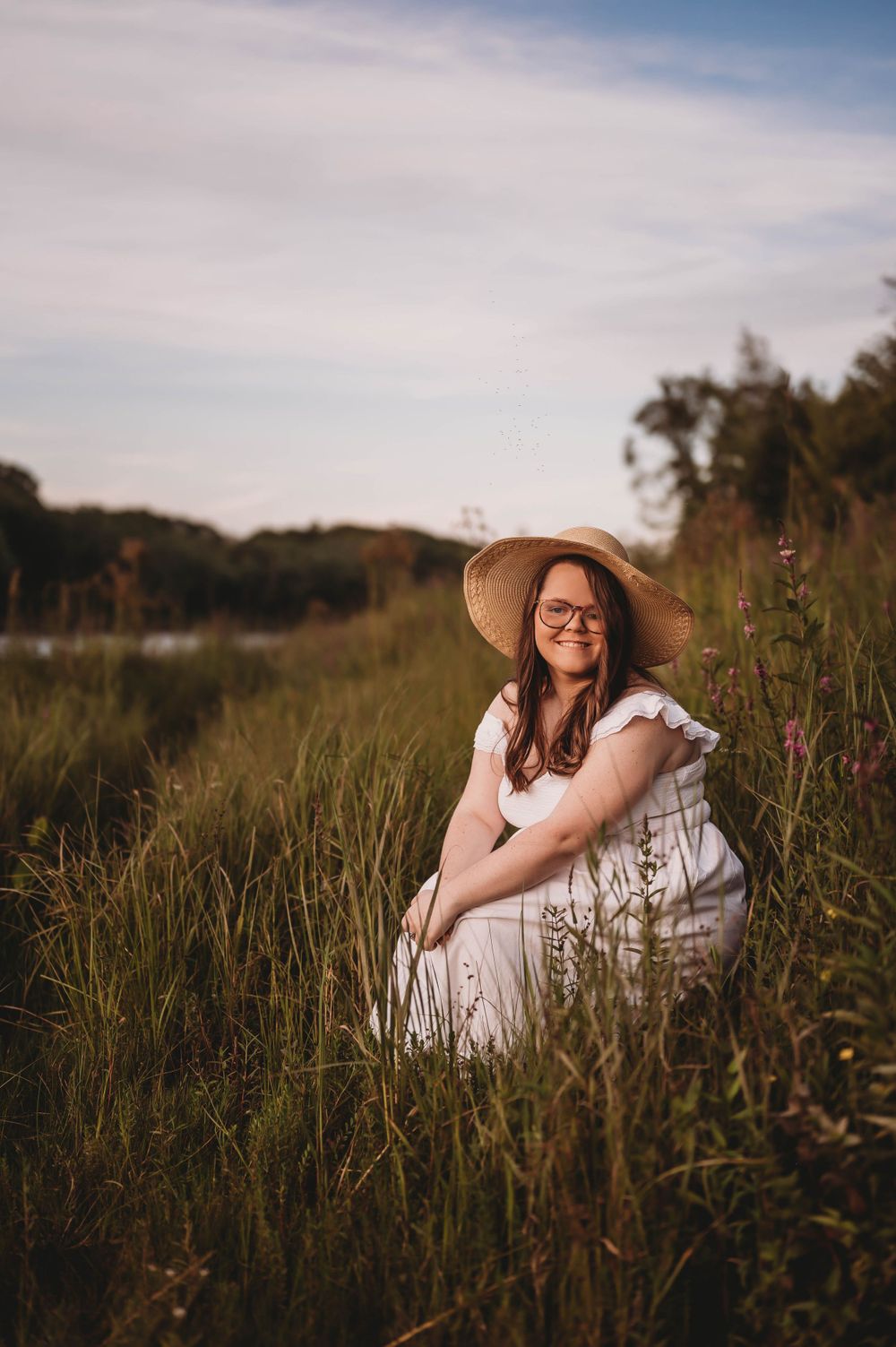 A dreamy sunset portrait in a wildflower meadow featuring a white dress and wide-brimmed sun hat.