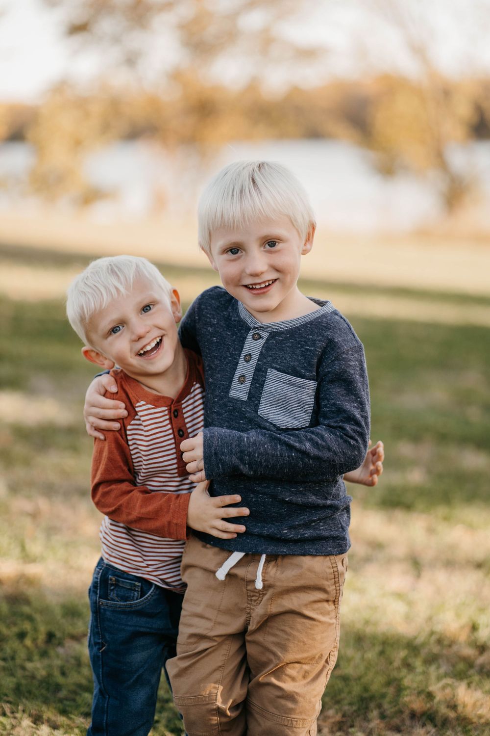 Two young children laughing and hugging outdoors in autumn light.