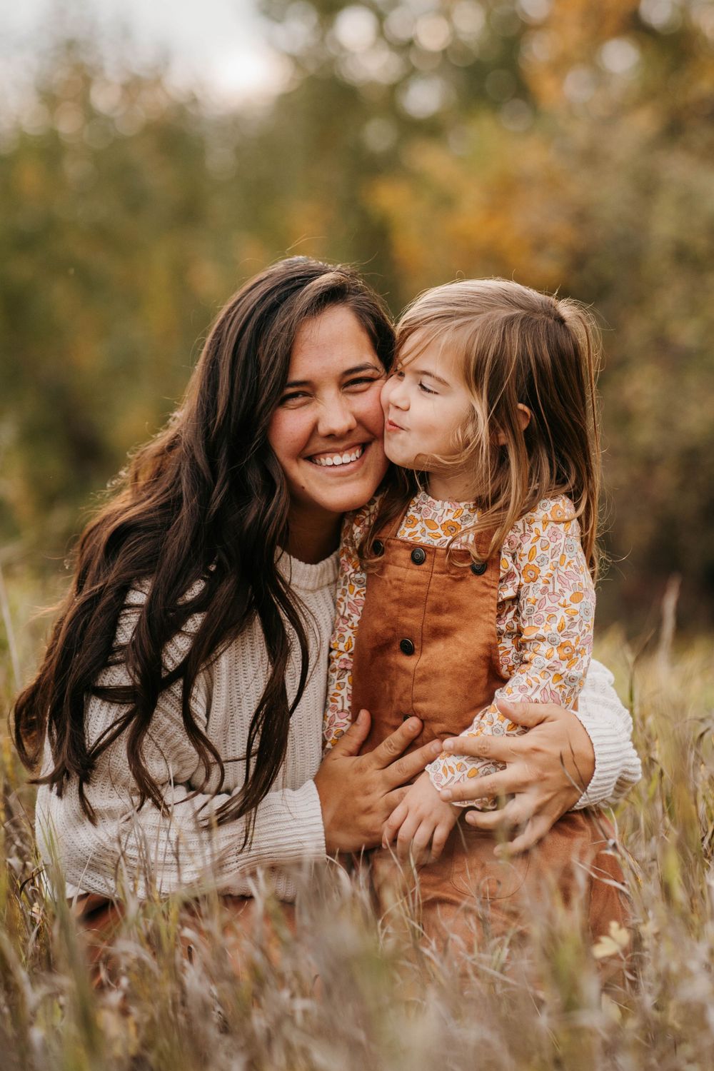 Mother and daughter sharing joyful moment together in autumn field.