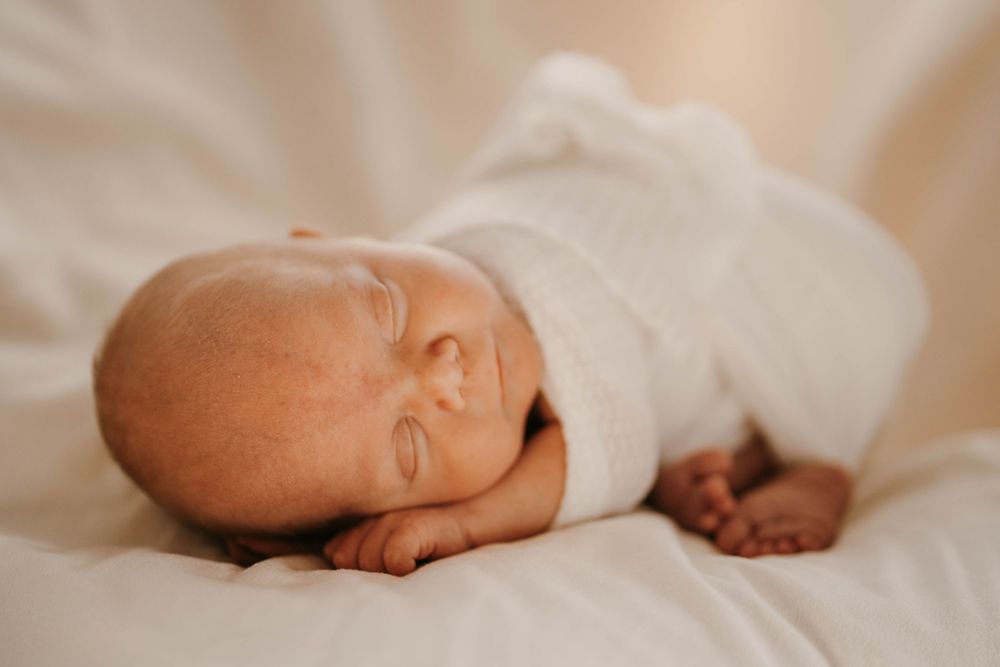 Close-up detail of tiny baby feet resting on white bedding.