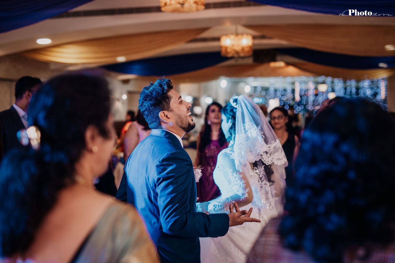 Wedding reception dance floor illuminated with blue lighting and chandelier.