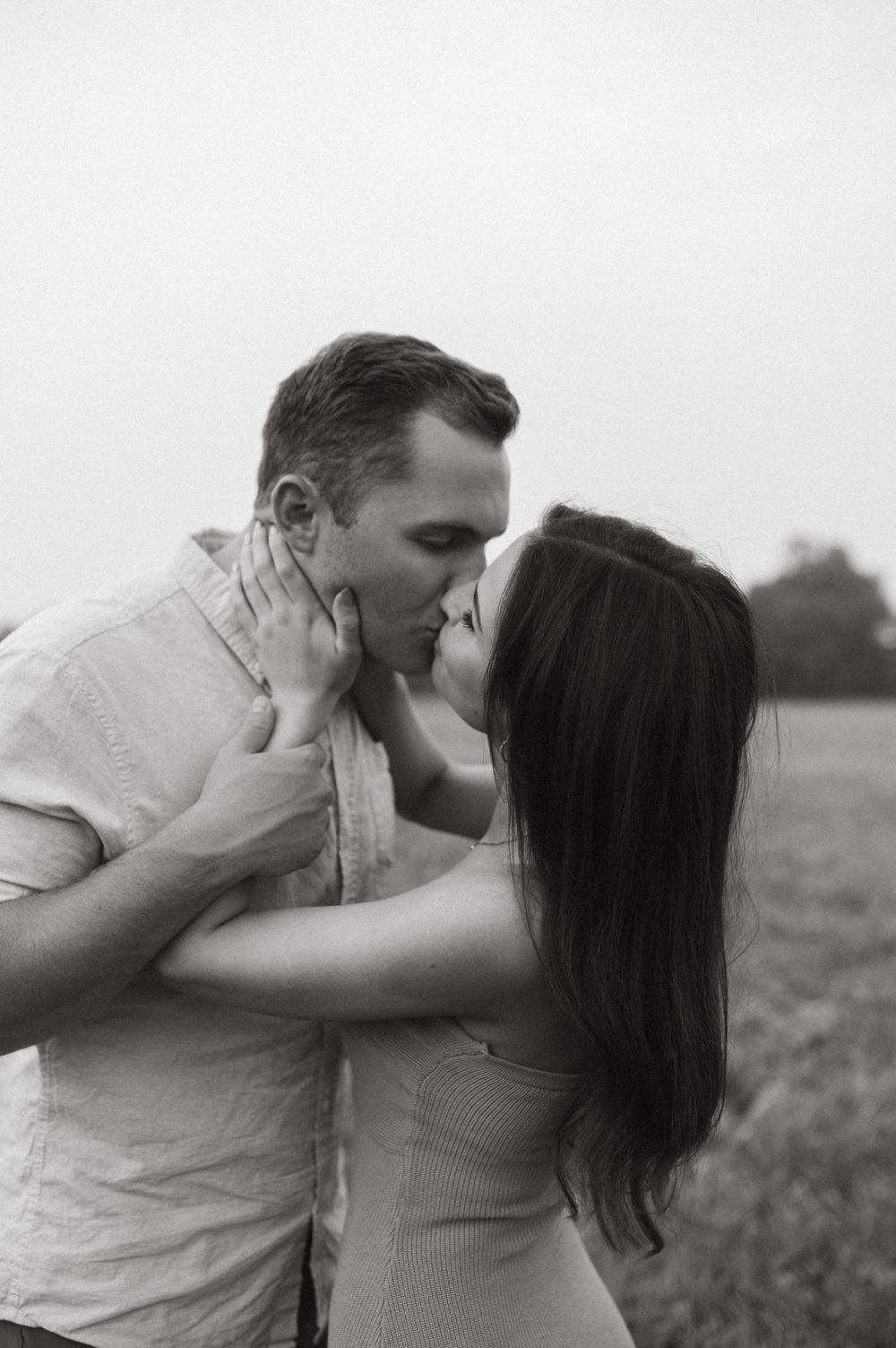 An intimate black and white photo of a couple sharing a passionate kiss.