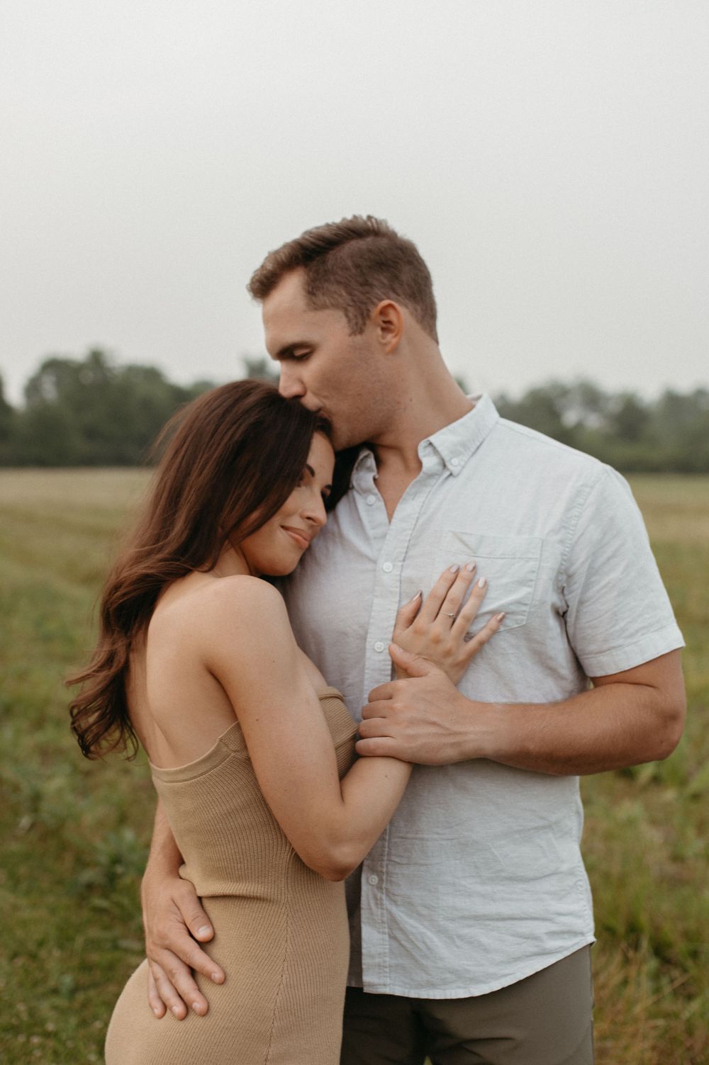 An intimate portrait of a couple sharing an affectionate moment in a countryside setting.