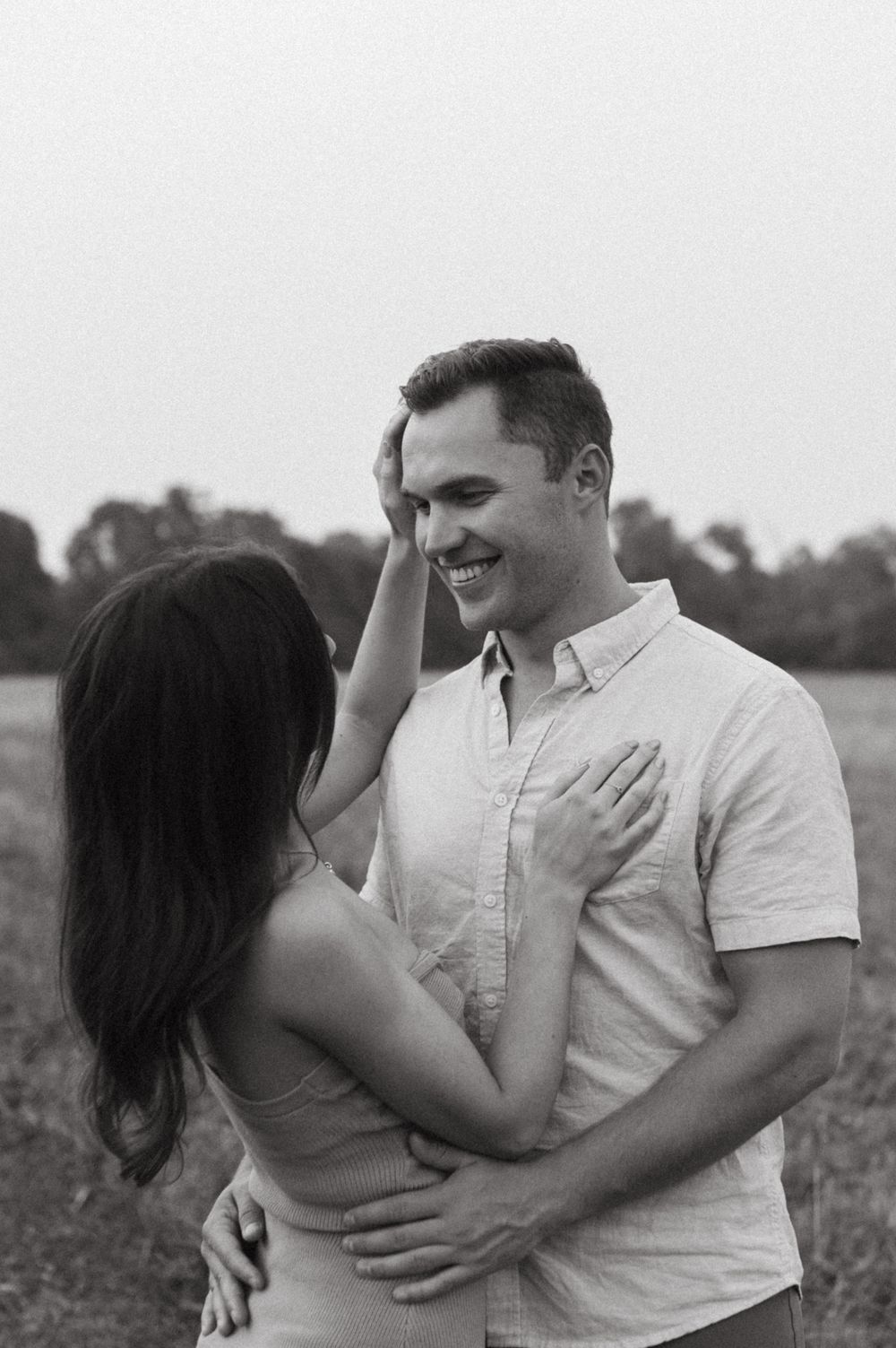 A tender moment shared between a couple in a serene field setting.