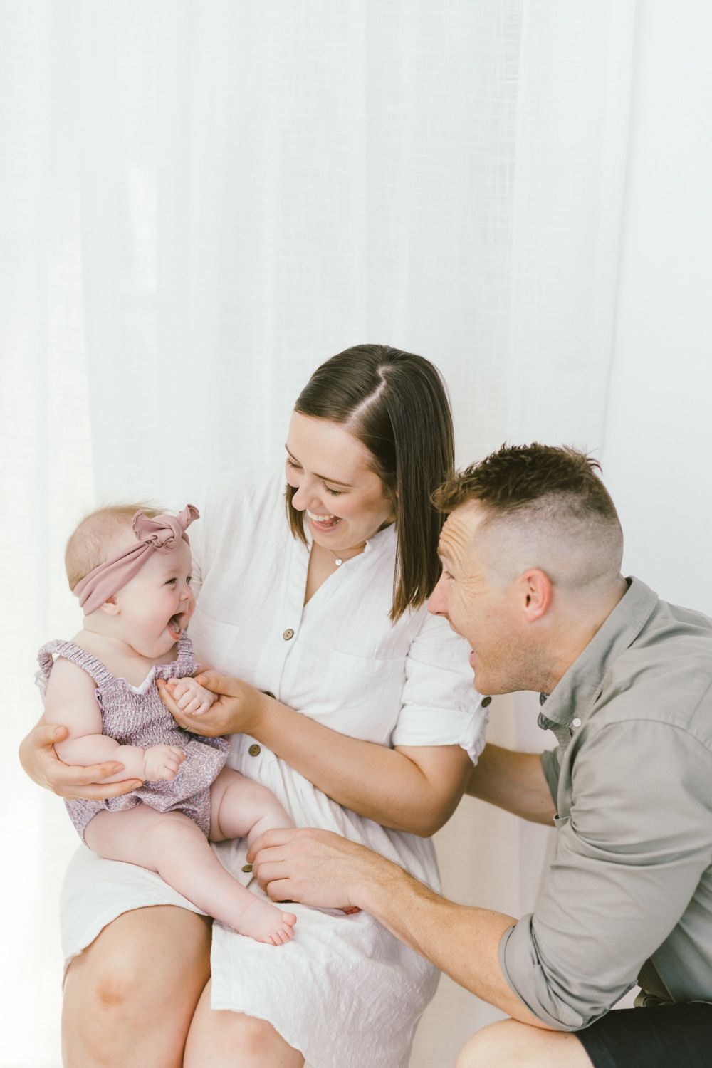 Candid family photo showing shared laughter against white background.