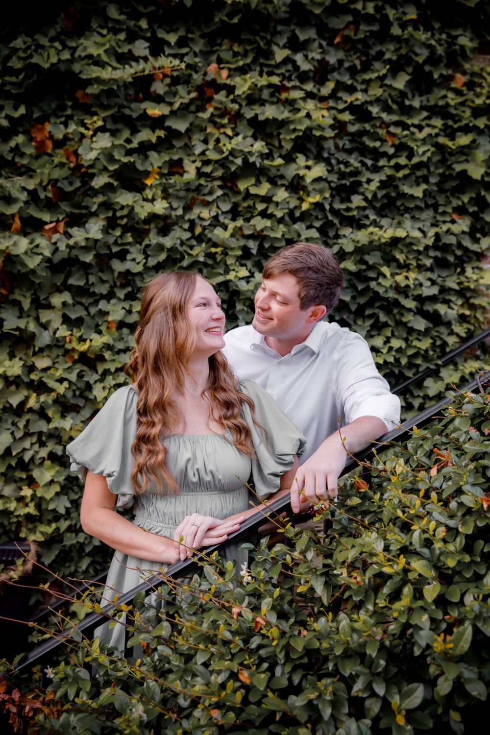 Romantic portrait of couple surrounded by lush ivy covered wall outdoors.